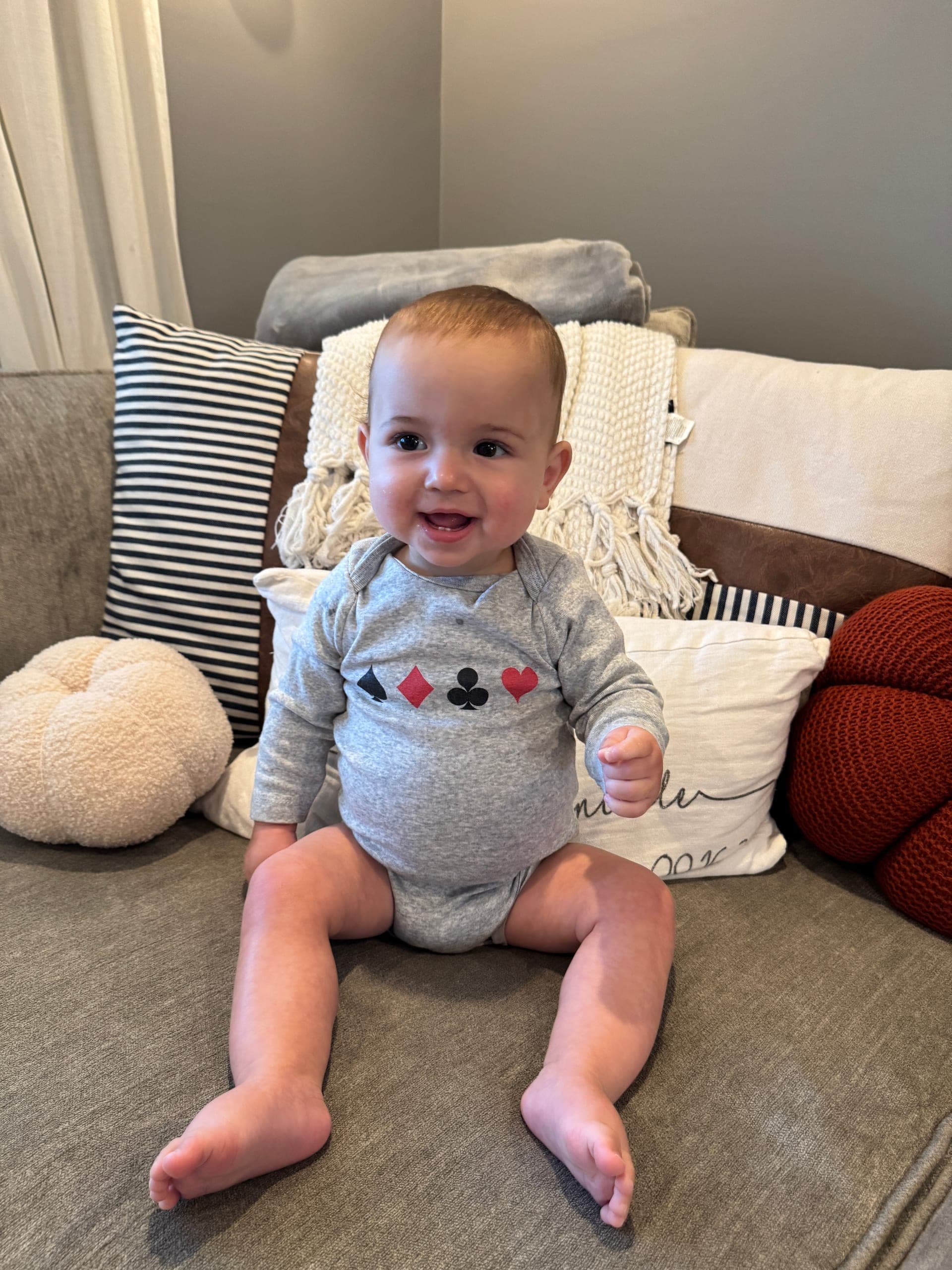 Brayden smiling in a onesie printed with the four playing-card suits