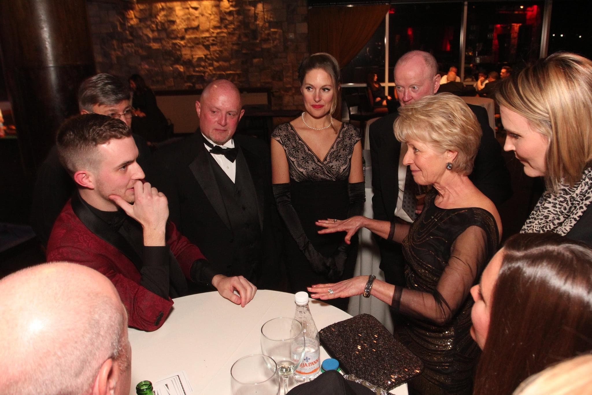 Chris Dare performing close-up magic at a black-tie gala table as guests in formalwear lean in and react