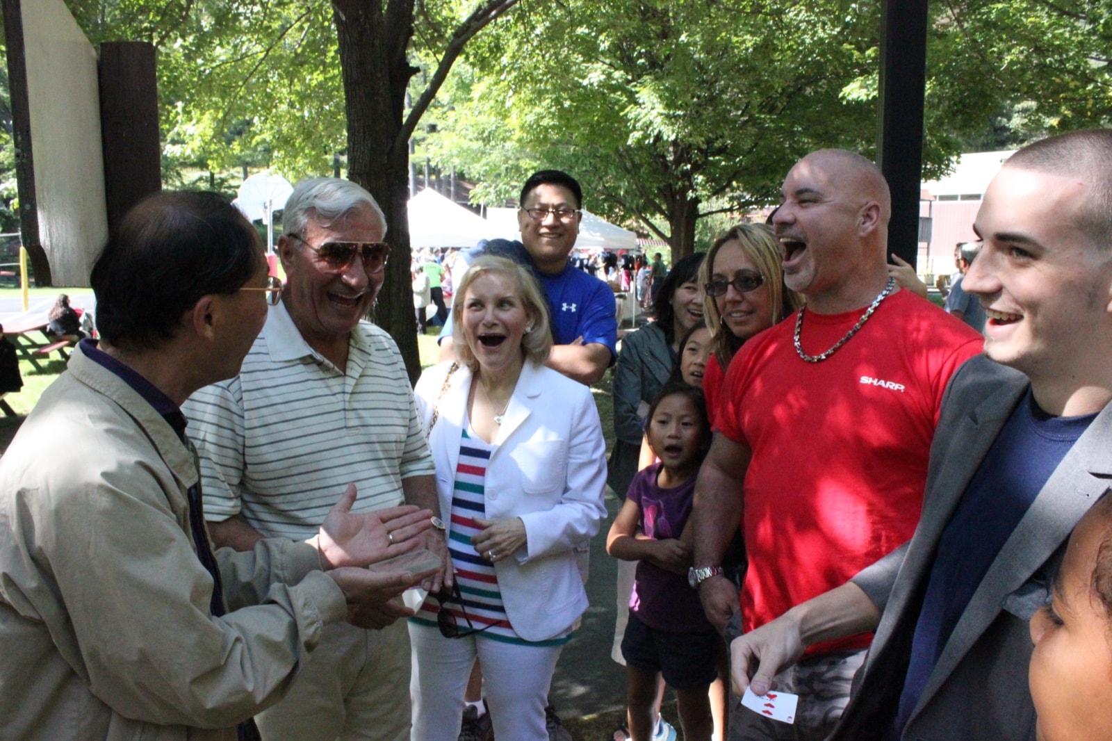 Guests laughing during an outdoor daytime performance by Chris Dare
