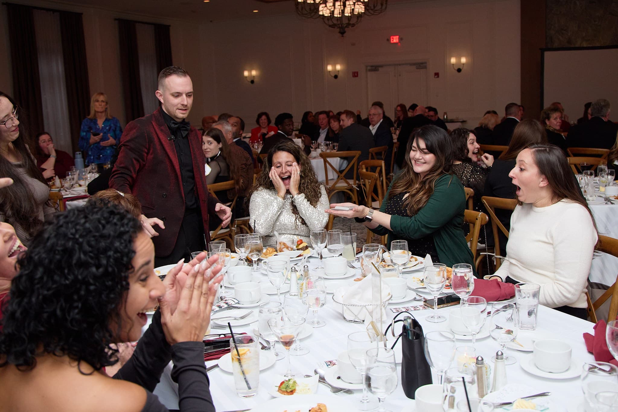 Chris Dare performing table to table at a New York gala dinner as the whole table reacts
