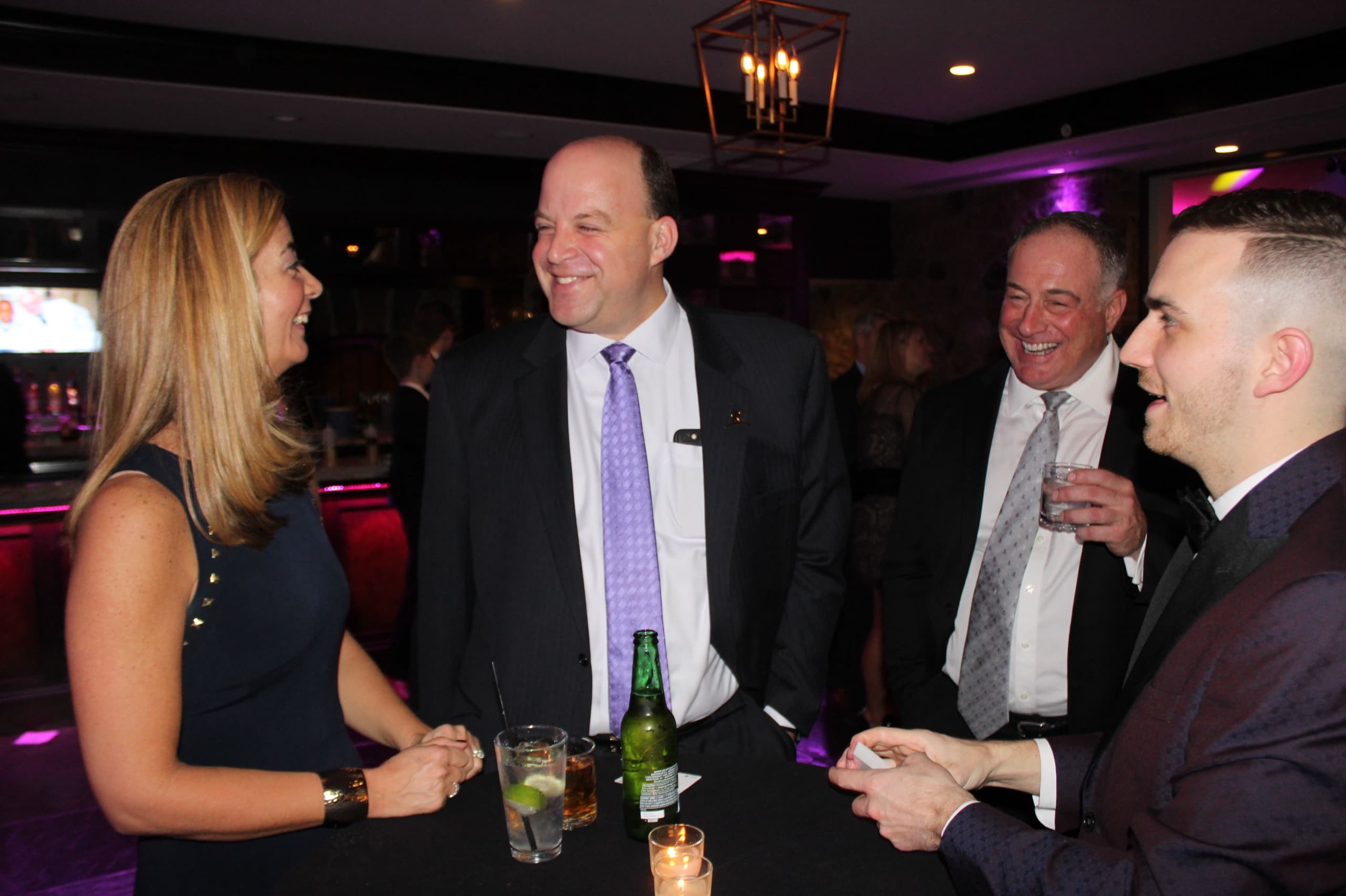 Chris Dare performing for three executives laughing around a cocktail table at a private event